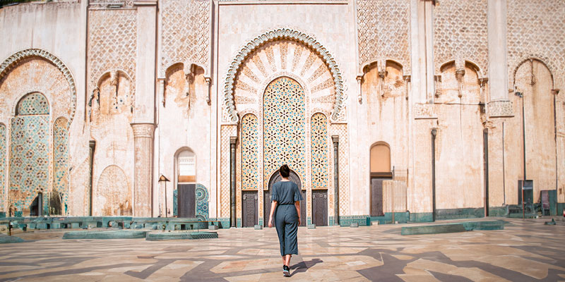 Menina caminhando em direção a uma grande porta árabe na Mesquita de Casablanca